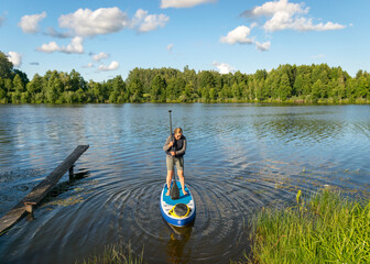 landscape with a woman on a sup board, sunny summer day by the lake, summer