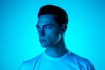 Look. Handsome caucasian man's portrait isolated on blue studio background in neon, monochrome....