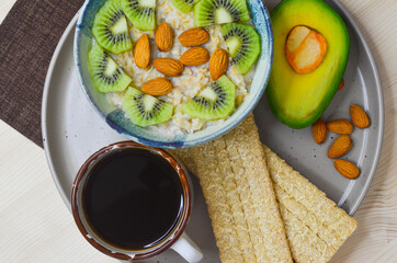 Healthy, natural and hearty breakfast, milk oatmeal with kiwi and almonds