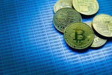 Selective focus of gold bitcoin on a paper of binary code.