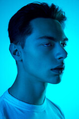 Style. Handsome caucasian man's portrait isolated on blue studio background in neon, monochrome. Beautiful male model. Concept of human emotions, facial expression, sales, ad, fashion and beauty.