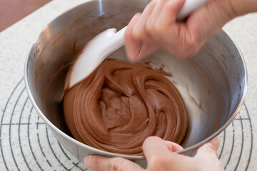 シリコンヘラでチョコレートケーキの生地を混ぜる様子