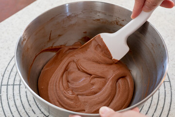 シリコンヘラでチョコレートケーキの生地を混ぜる様子