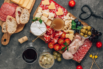 Assortment of spanish tapas or italian antipasti with meat, ham, olives, cheese, nuts and honey mustard sauce on a concrete background. Romantic dinner with wine. Top view Flat lay. Copy space