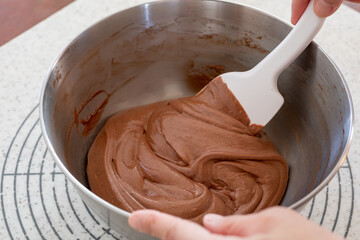 シリコンヘラでチョコレートケーキの生地を混ぜる様子