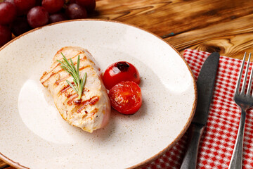 Grilled chicken breast served with cherry tomatoes on table