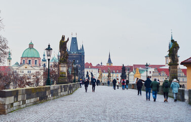 Prague, Czech Republic - January 7 2021: Occasional tourists take a stroll across empty Charles Bridge                                                              