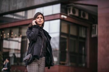 Beautiful young business woman talking on phone in city. Female using mobile phone on the street