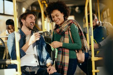 Happy couple having fun and talking while commuting by bus.