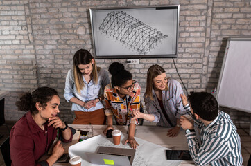Group of young people discussing architectural designs in the creative office.	