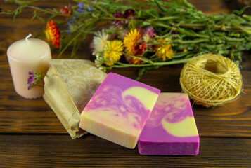 Natural handmade skincare. Handmade natural soap, candles and flowers on the dark wooden countertop.