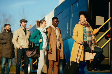 Group of happy people getting in a bus at the station. © Drazen