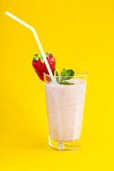 Milk strawberry smoothie made from fresh fruits on a bright background. Strawberry cocktail. A glass of delicious milk cocktail with strawberries and mint leaf. Copy space.