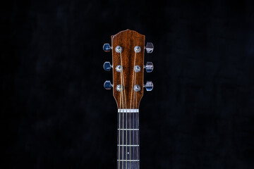acoustic guitar head with chrome tuning pegs and fretboard on isolated black background