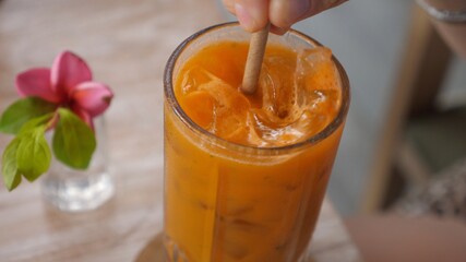 Close up of paper straw stirring fresh carrot juice with ice