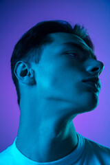 Shine. Handsome caucasian man's portrait isolated on purple studio background in neon, monochrome. Beautiful male model. Concept of human emotions, facial expression, sales, ad, fashion and beauty.