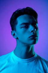 Mood. Handsome caucasian man's portrait isolated on purple studio background in neon, monochrome. Beautiful male model. Concept of human emotions, facial expression, sales, ad, fashion and beauty.