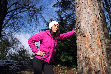 Sportswoman in winter clothes taking a break after training in the park. Fitness and recreation.