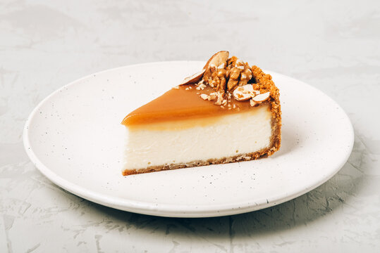 A piece of cheesecake with salted caramel and nuts on a plate.