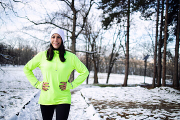 Sportswoman in winter training clothes about to start running training on snow.