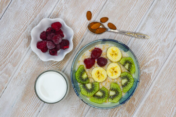 Healthy food for breakfast top view flat lay. Oatmeal porridge with milk, kiwi and banana fruit and raspberry