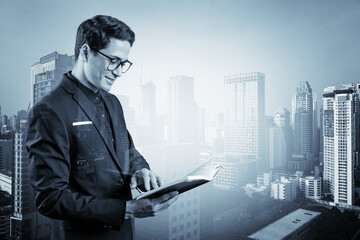 Young handsome businessman in suit and glasses thinking how to tackle the problem, new career opportunities, MBA assignment. Bangkok on background. Double exposure.