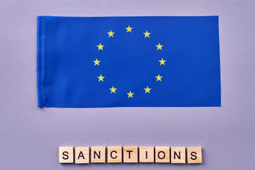 European Union flag. Sanctions word made of wooden cubes.