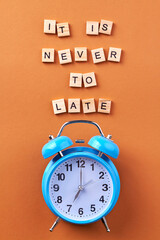 Its never too late. Vertical shot alarm clock on orange background.