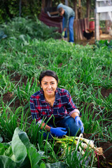 Female gardener with green onion on the field