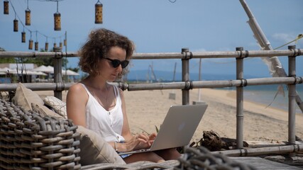 Work from the beach. Young woman works on her computer while enjoying sun and the see