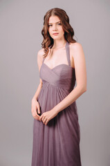 Fototapeta premium Elegant dress. Beautiful lilac chiffon evening gown. Studio portrait of young brunette woman.