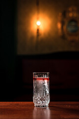 A long drink transparent layered cocktail with ice in a highball glass in a bar