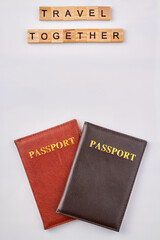 Travel together made from wooden letter blocks. Red and black passports on white background.