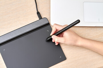 Girl draws on a graphics tablet with pen. Close-up, selective focus