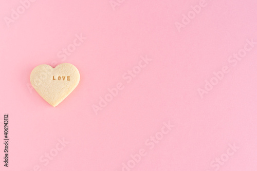 Heart shaped cookie with the word LOVE on a pink background Valentine's Day, Mother's Day, anniversary.