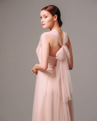 Elegant salmon dress with bow. Beautiful pink chiffon evening gown. Studio portrait of young brunette woman. Transformer dress idea for celebration. Bridesmaid dresses. © Love-Pics