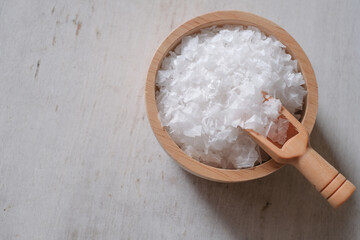 Flower of salt, is a salt that forms as a thin, delicate crust on the surface of seawater in the wooden scoop and wooden bowl on wooden background.