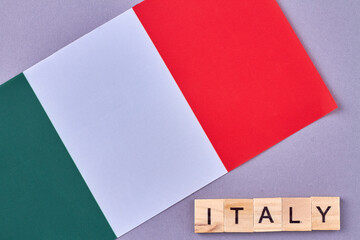 National flag of Italy. Wooden cubes with letters isolated on violet background.