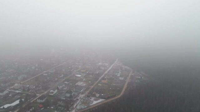 Gloomy aerial reveal of countryside village housees descending from clouds