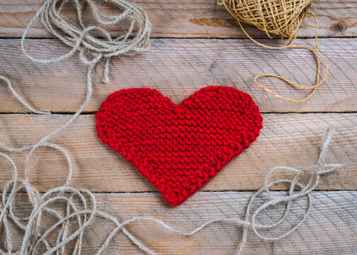 Wooden background decorated with handmade knitted heart for Valentine's Day