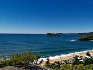 Fototapeta na wymiar Beautiful view of a deep blue sea with white sandy beach, small island and deep blue sky in the background, Mount Ettalong Lookout, Pearl Beach, Brisbane Water National Park, New South Wales, Australi