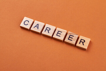 Career word written with wooden cubes. Alphabet blocks with letters isolated on orange background.