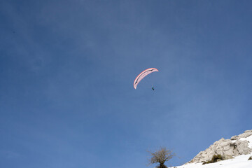 Paraglider flying over the mountains in winter