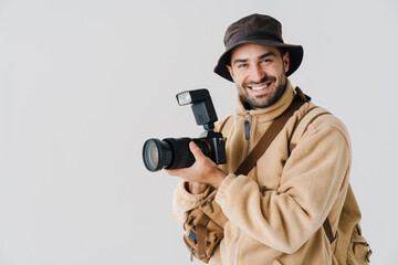 Joyful handsome photographer in hat posing with digital camera