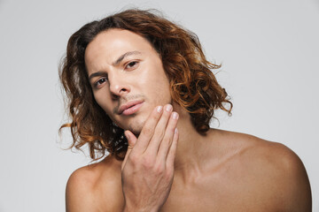 Confident shirtless guy touching his face and looking at camera