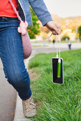 Girl holds by cable a smartphone and an external power bank while charging