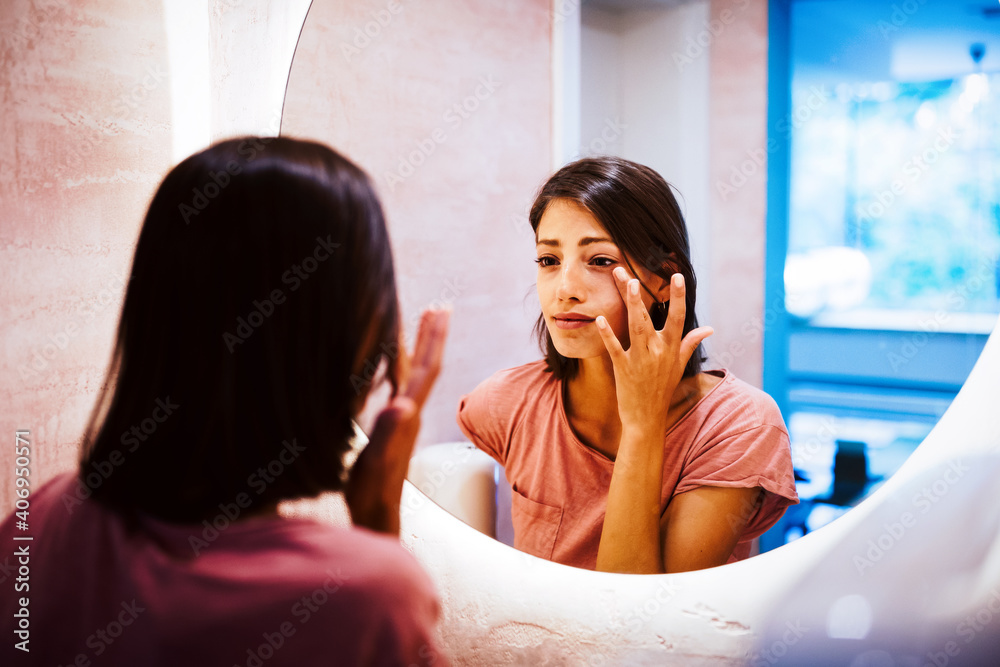 Wall mural Mirror reflection of a woman worrying because of wrinkles on her forehead.