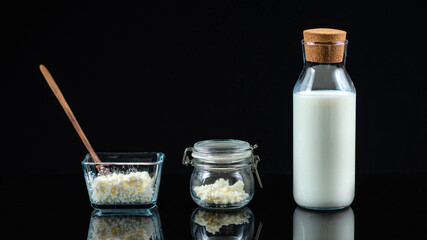 Kefir Probiotic Grains. Kefir Grains in a Bowl and Jar, and Bottle of Milk on Black Background.