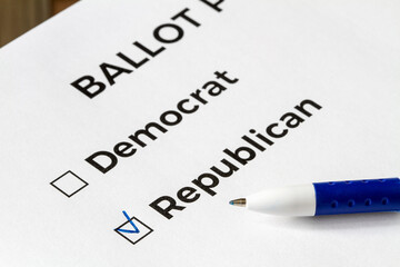 Obraz premium Checklist concept. Closeup of ballot paper with words Democrat and Republican and a pen on it. A checkmark for Republican in the checkbox.