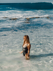 Attractive woman in black swimwear, caucasian model posing at ocean beach